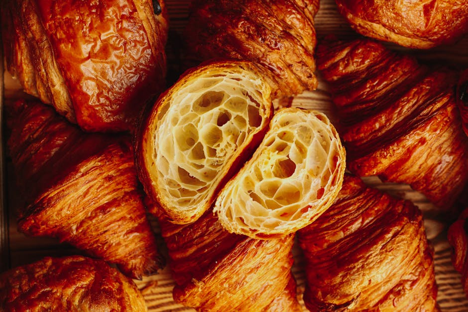 Golden brown croissants showcasing flaky texture in a bakery setting.