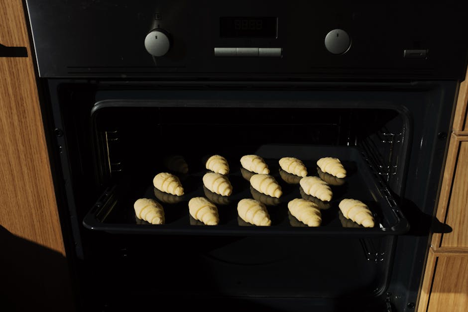 Close-up of fresh croissants baking in the oven, showcasing their golden, flaky texture.